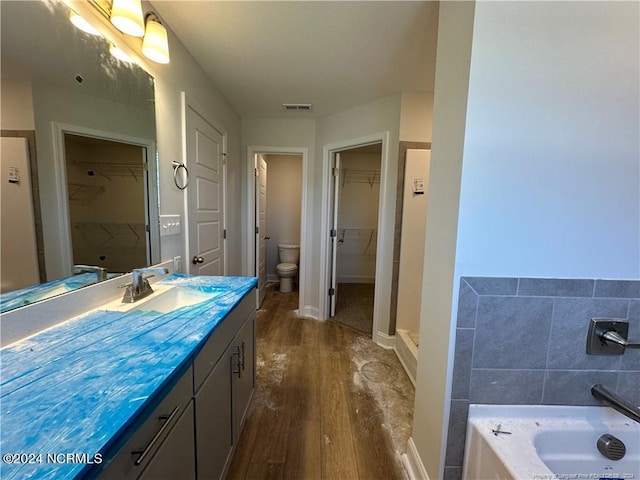 bathroom with vanity, hardwood / wood-style floors, a bathtub, and toilet