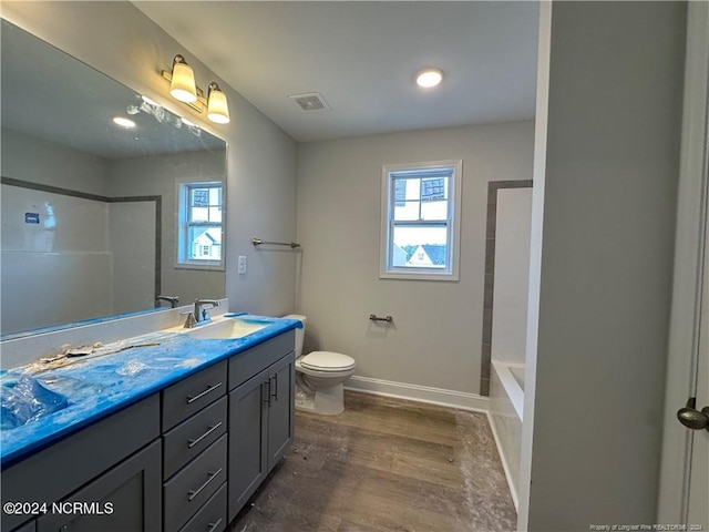 full bathroom with a healthy amount of sunlight, vanity, hardwood / wood-style flooring, and toilet