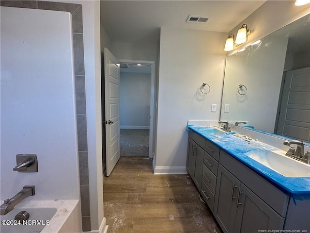 bathroom featuring vanity, hardwood / wood-style floors, and a tub to relax in