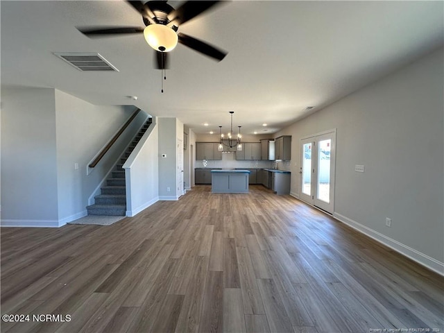 unfurnished living room with dark wood-type flooring, sink, and ceiling fan with notable chandelier