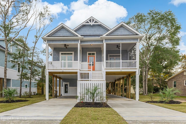 coastal inspired home with ceiling fan, a front lawn, a porch, and a carport