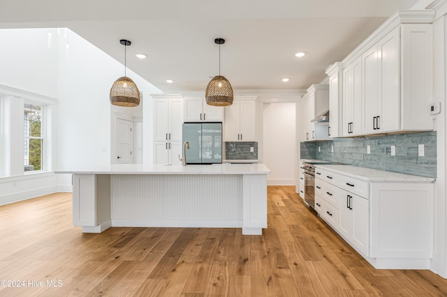 kitchen with white cabinets, decorative light fixtures, light hardwood / wood-style flooring, and stainless steel appliances