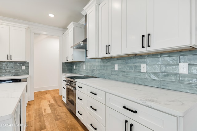 kitchen with white cabinetry, wall chimney exhaust hood, backsplash, high end range, and light wood-type flooring