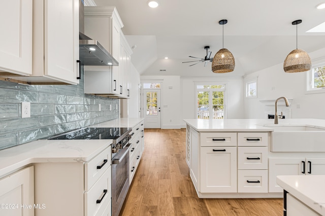 kitchen featuring sink, stainless steel stove, light hardwood / wood-style flooring, a healthy amount of sunlight, and white cabinetry