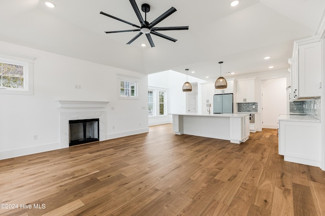 unfurnished living room featuring ceiling fan, a fireplace, lofted ceiling, and light wood-type flooring