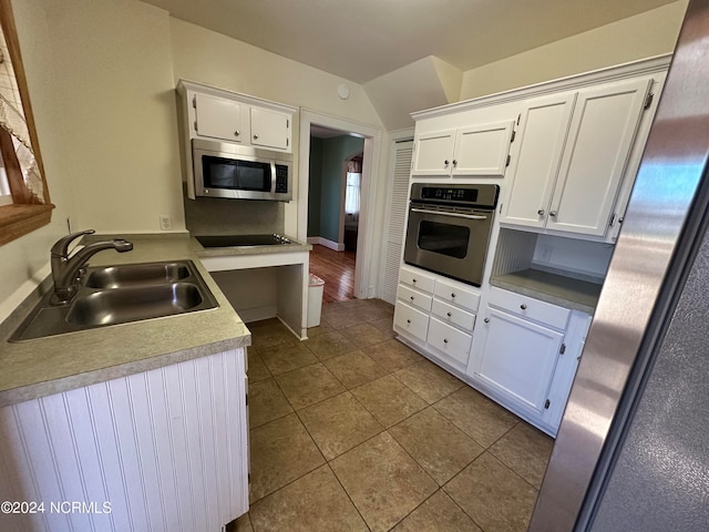 kitchen with stainless steel appliances, white cabinets, sink, and light tile patterned floors