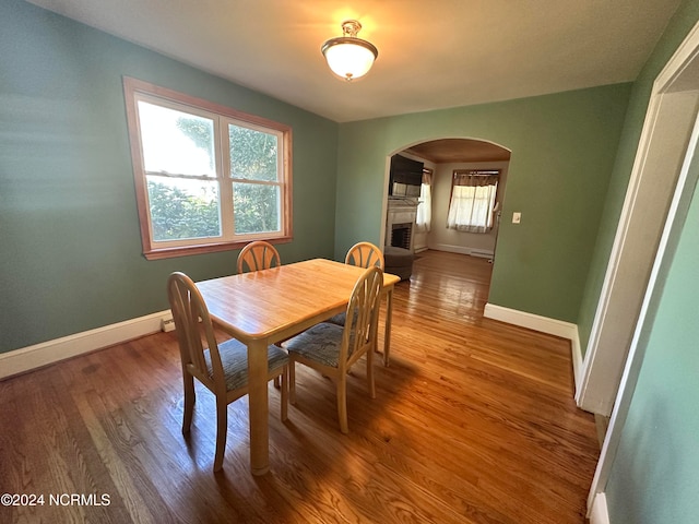 dining room featuring hardwood / wood-style flooring, a fireplace, plenty of natural light, and a baseboard heating unit