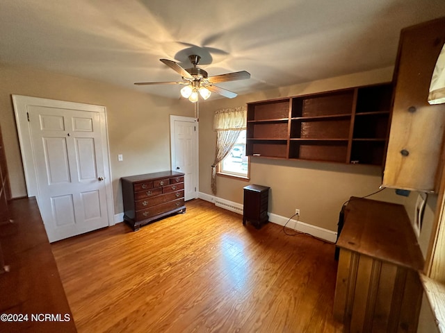 unfurnished bedroom with baseboard heating, ceiling fan, and light hardwood / wood-style flooring