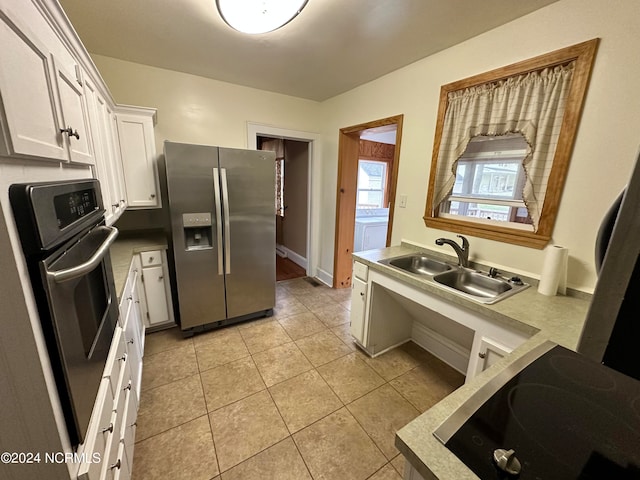 kitchen featuring washer / dryer, white cabinets, sink, appliances with stainless steel finishes, and light tile patterned floors