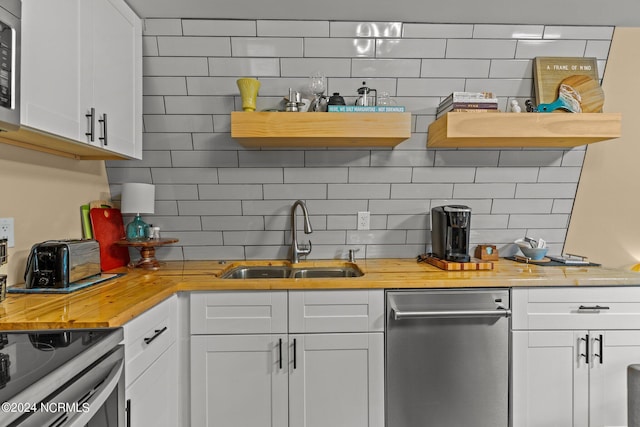 kitchen featuring white cabinets, wooden counters, open shelves, a sink, and decorative backsplash