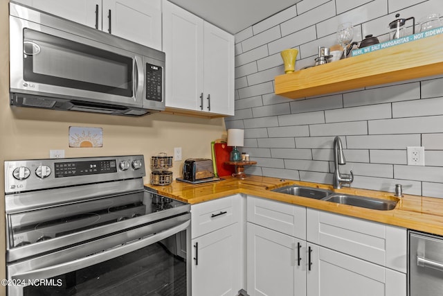 kitchen with stainless steel appliances, a sink, backsplash, butcher block countertops, and open shelves
