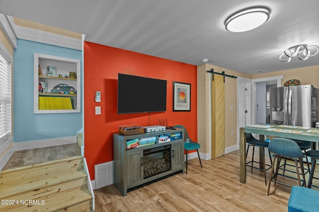 interior space featuring a barn door, light hardwood / wood-style floors, and stainless steel refrigerator with ice dispenser