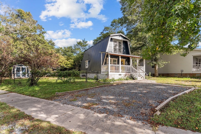 a-frame style home with a gambrel roof, crawl space, covered porch, and fence