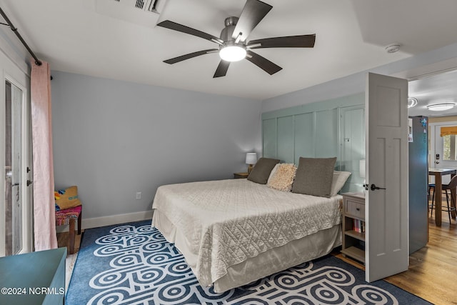 bedroom featuring wood finished floors, a ceiling fan, and baseboards