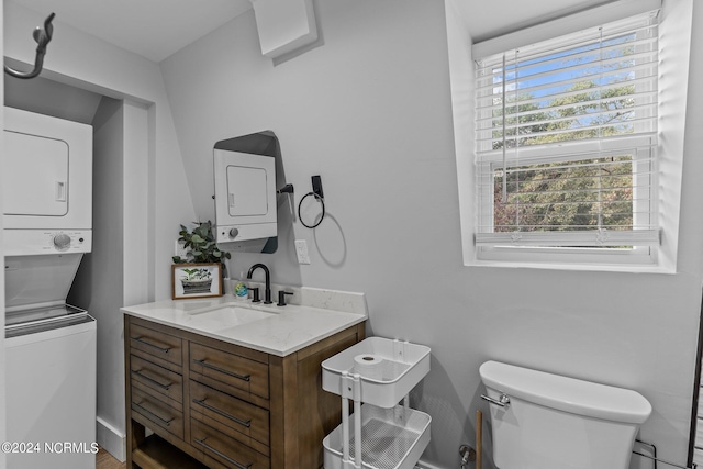 half bathroom featuring stacked washer and clothes dryer, vanity, and toilet