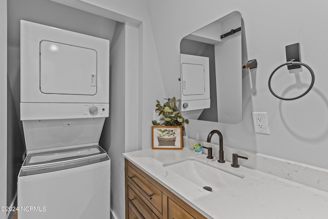 clothes washing area featuring stacked washer and dryer, laundry area, and a sink