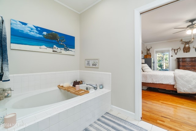 bathroom with ceiling fan, a relaxing tiled tub, ornamental molding, and tile patterned floors