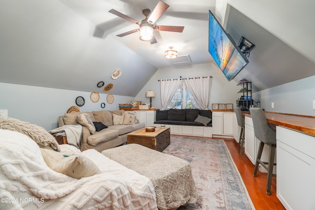 living room featuring ceiling fan, vaulted ceiling, and wood-type flooring