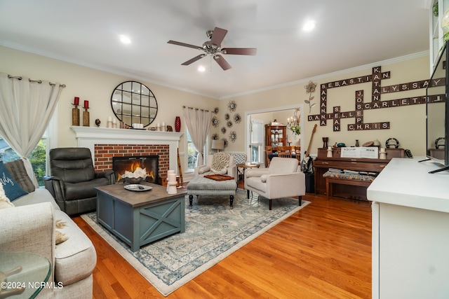 living room with ceiling fan with notable chandelier, crown molding, a fireplace, and wood-type flooring