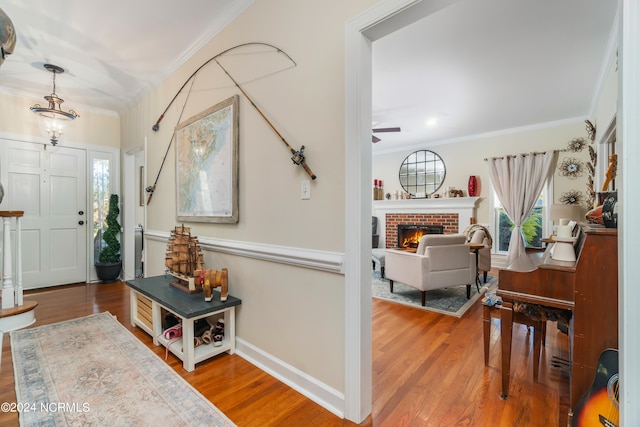 foyer entrance with a fireplace, crown molding, hardwood / wood-style floors, and ceiling fan