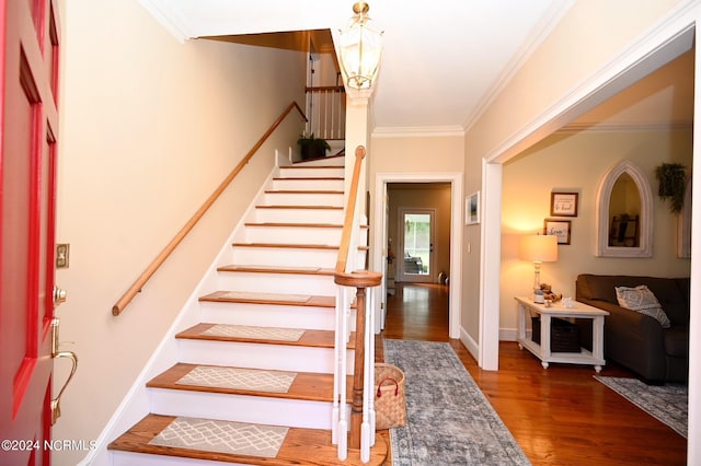 stairway with ornamental molding and hardwood / wood-style flooring