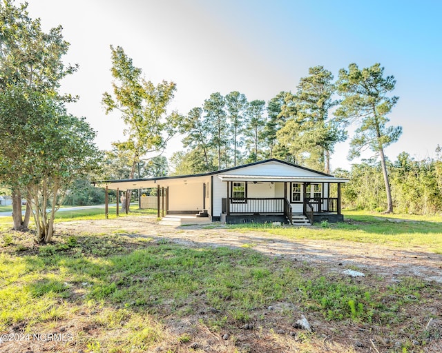 exterior space featuring a front lawn, covered porch, and a carport