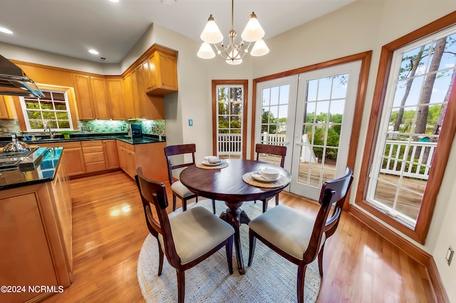 dining room featuring a notable chandelier, sink, and light hardwood / wood-style floors