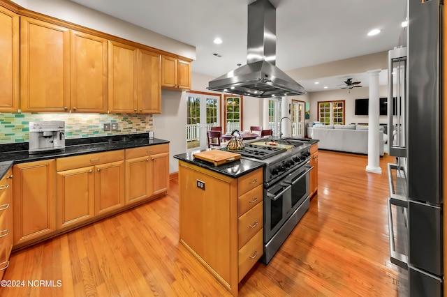 kitchen with premium appliances, island exhaust hood, light wood-type flooring, and decorative backsplash