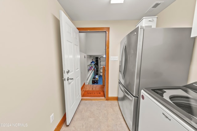 kitchen with washer / clothes dryer, stainless steel refrigerator, and white cabinetry