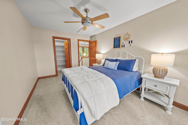 bedroom with a closet, a walk in closet, carpet, and ceiling fan