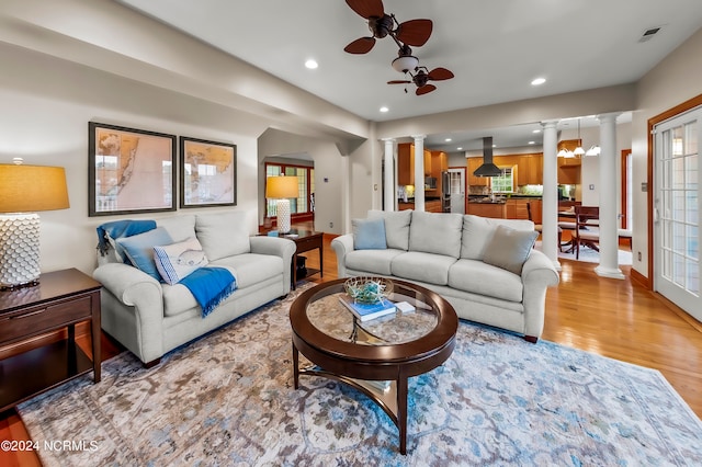 living room featuring ceiling fan, hardwood / wood-style flooring, and decorative columns