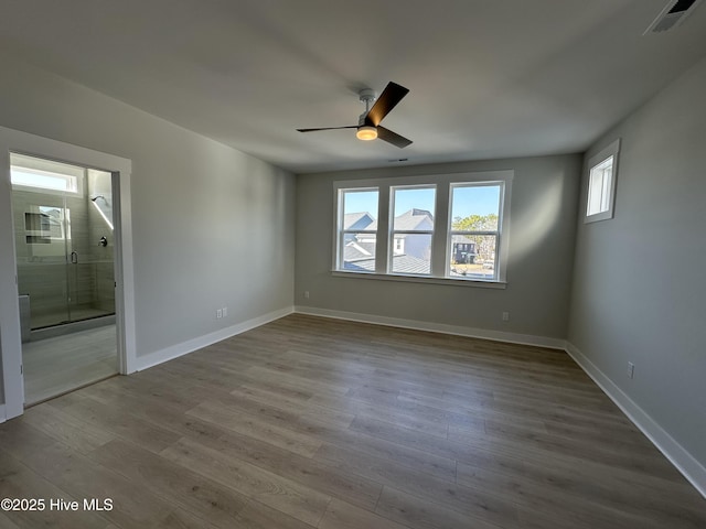 unfurnished room featuring a ceiling fan, wood finished floors, visible vents, and baseboards