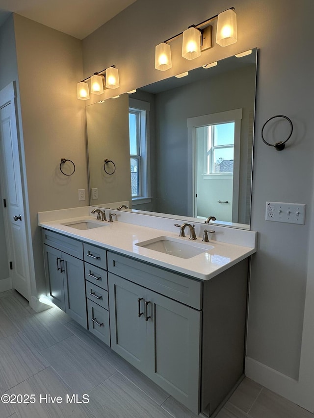 full bathroom featuring a sink, baseboards, and double vanity