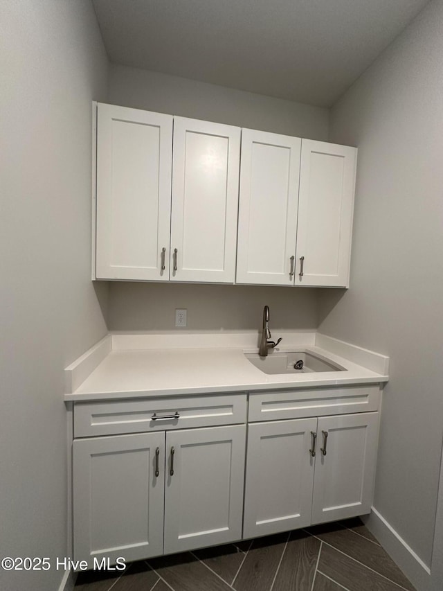 laundry area with a sink and baseboards