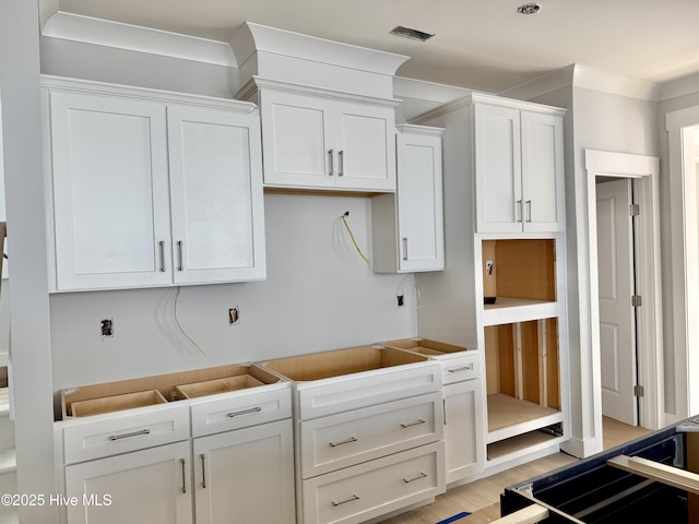 kitchen with white cabinetry, ornamental molding, and light hardwood / wood-style floors