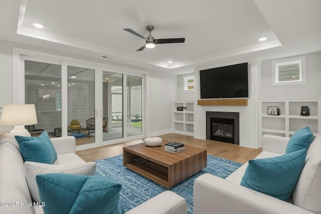 living room featuring hardwood / wood-style flooring, a fireplace, and a tray ceiling