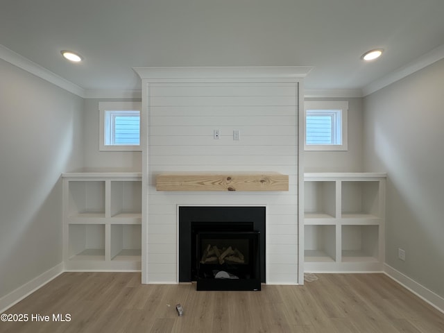 unfurnished living room featuring ornamental molding, a fireplace, baseboards, and wood finished floors