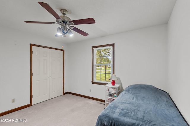 bedroom featuring a closet, light carpet, a textured ceiling, and ceiling fan