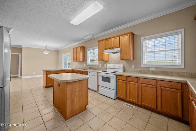 kitchen with hanging light fixtures, plenty of natural light, white appliances, and a center island