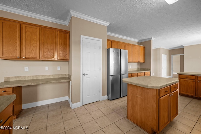 kitchen with light tile patterned floors, stainless steel fridge, ornamental molding, and a kitchen island