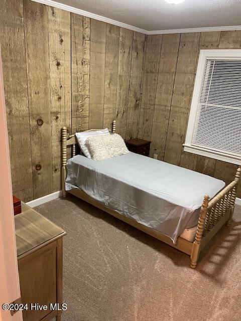 bedroom featuring carpet floors, crown molding, and wood walls