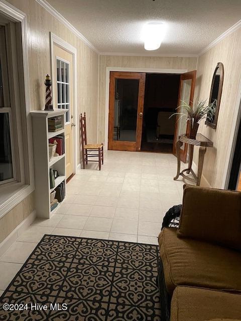 corridor with crown molding, light tile patterned flooring, and a textured ceiling