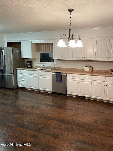 kitchen with stainless steel appliances, white cabinetry, pendant lighting, and a notable chandelier