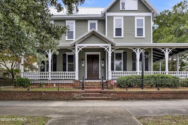 victorian-style house featuring metal roof, a porch, and fence