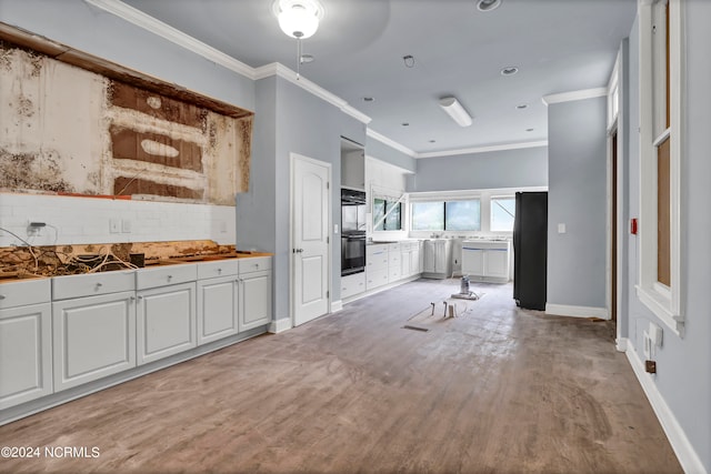 kitchen featuring black appliances, light wood-type flooring, decorative backsplash, white cabinets, and ornamental molding