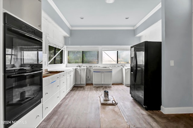 kitchen with white cabinetry, crown molding, hardwood / wood-style flooring, and black appliances