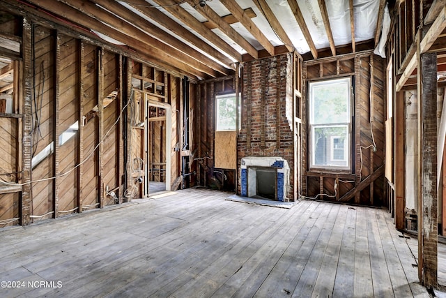 miscellaneous room featuring wood walls, a brick fireplace, and hardwood / wood-style floors