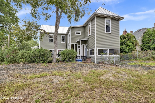 view of front of house featuring fence, a standing seam roof, and metal roof