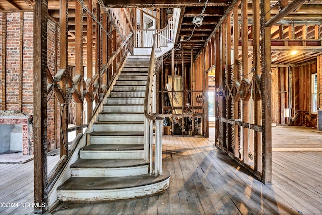 stairs featuring brick wall and hardwood / wood-style flooring