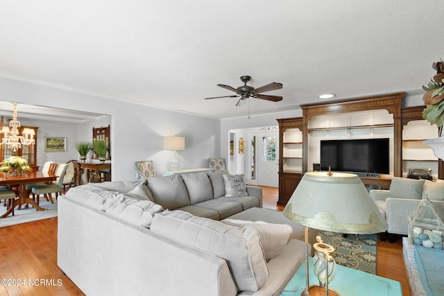 living room featuring ceiling fan with notable chandelier, ornamental molding, light hardwood / wood-style floors, and a textured ceiling